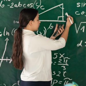 Girl writes mathematical examples on the school board. solves a geometry problem.
