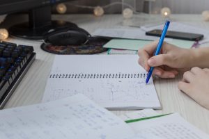 La mano de una mujer escribe fórmulas matemáticas en un cuaderno primer plano