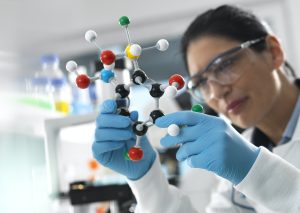 أبحاث التكنولوجيا الحيوية ، عالم يفحص نموذجًا جزيئيًا كرويًا وعصا
