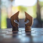 Closeup image of two horses on wooden chessboard game
