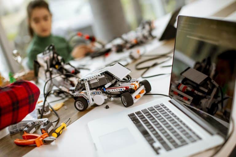 Niños felices programando juguetes eléctricos y robots en el aula de robótica