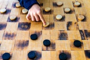 Child's hands moving pieces of Checkers game, concepts of struggle, strategy and confrontation.