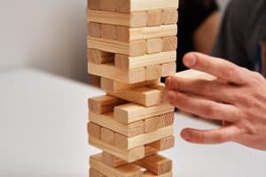 Family play board game. Hands take wooden block from tower