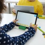 Niños multiétnicos en clase de tecnología codificando un robot en una tableta