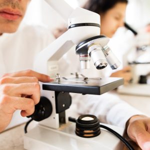 Unrecognizable high school students with microscopes.